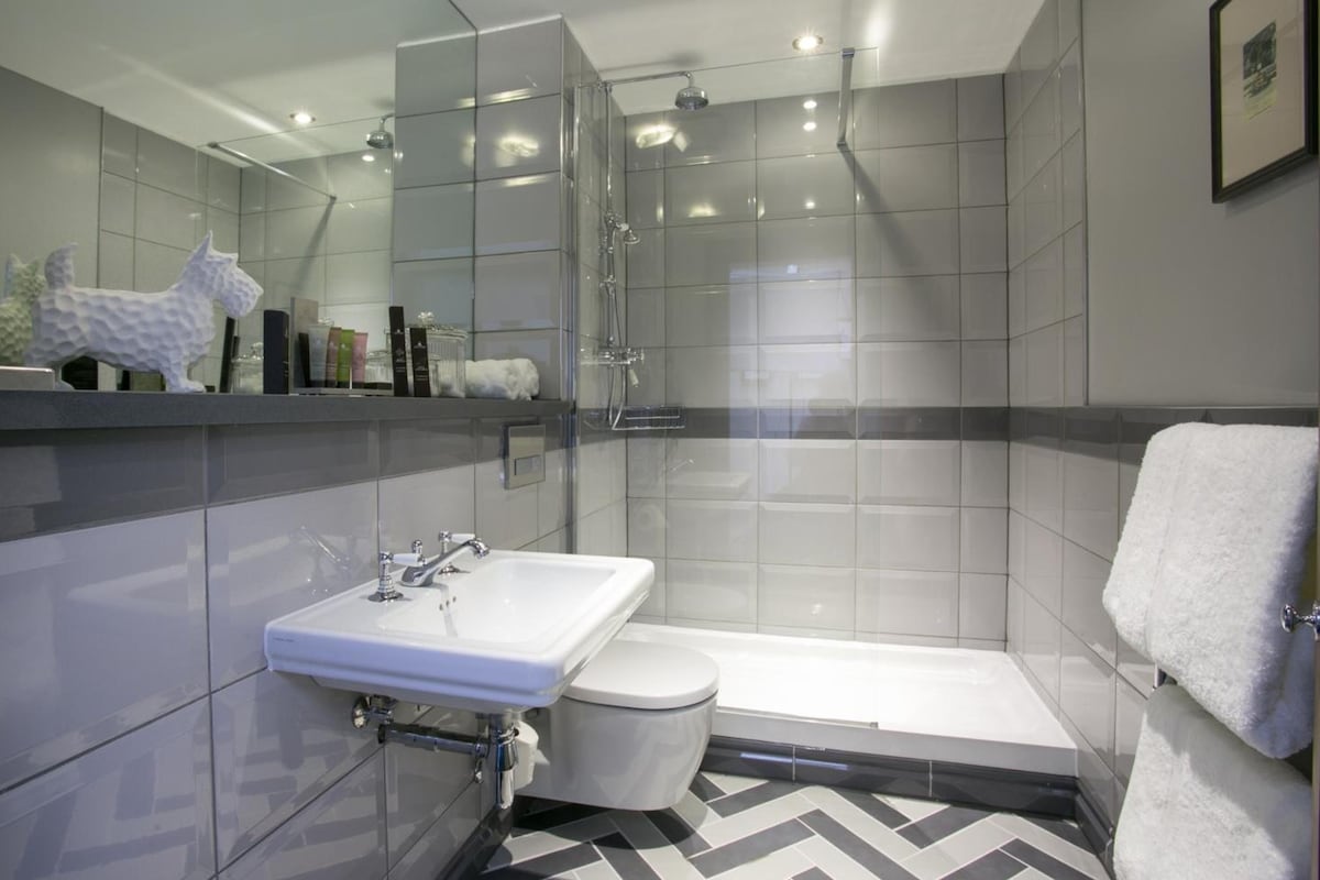 A modern bathroom with a glass shower enclosure, a white sink, and a toilet.
