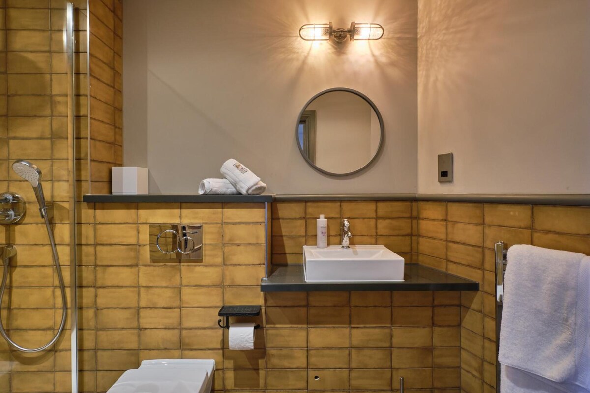 A bathroom with a shower, a sink, a mirror, and a towel rack.