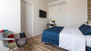A hotel room with a bed, a desk, a chair, a TV, and a wall-mounted air conditioner. - Aparthotel Isola (Milan)