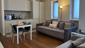 A compact living space with a kitchenette, a dining area, and a sofa with decorative pillows. - Aparthotel Isola (Milan)