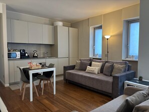 A compact living space with a kitchenette, a dining area, and a sofa with decorative pillows. - Aparthotel Isola (Milan)