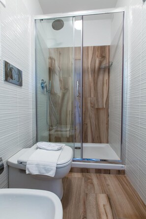 A modern bathroom with a glass-enclosed shower, a toilet, and a bathtub. - Aparthotel Isola (Milan)