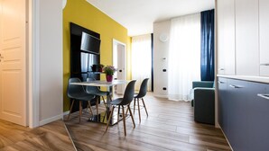 A modern kitchen with a flat-screen TV, a dining area with a table and chairs, and a living space with a sofa and curtains. - Aparthotel Isola (Milan)