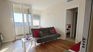 A modern living room with a grey sofa, a small white table, and a red chair. - Aparthotel Isola (Milan)