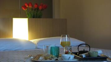 Un vassoio colazione ordinato su un letto, con un vaso di tulipani rossi sullo sfondo.