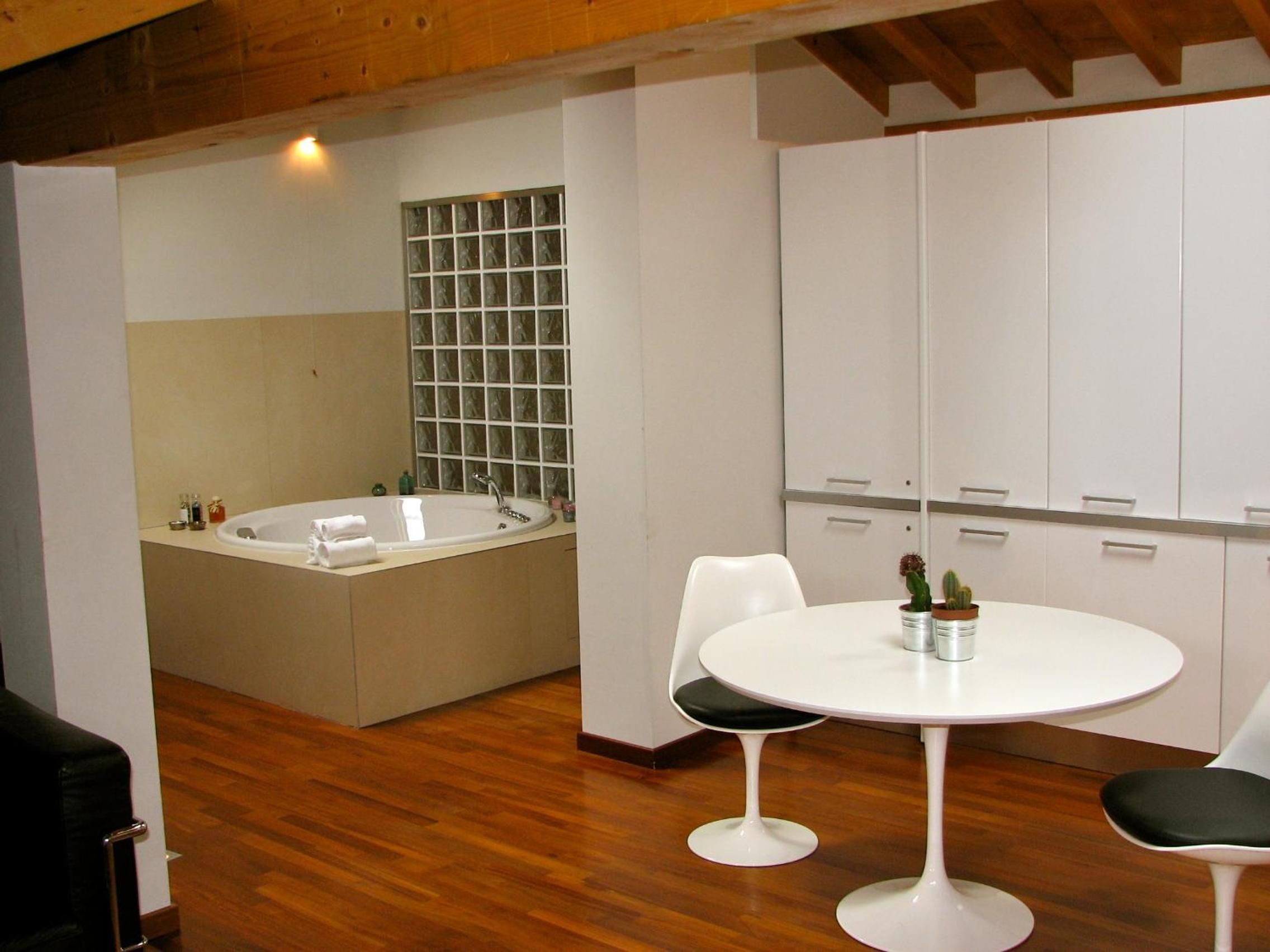 A modern bathroom with a bathtub, a sink, and a shower area. There is a round table with chairs and a potted plant.