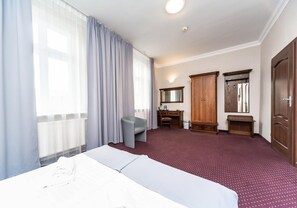 A hotel room with a bed, a desk, a chair, a wardrobe, and a mirror. - Hotel Marczewski (Bielsko-Biala)