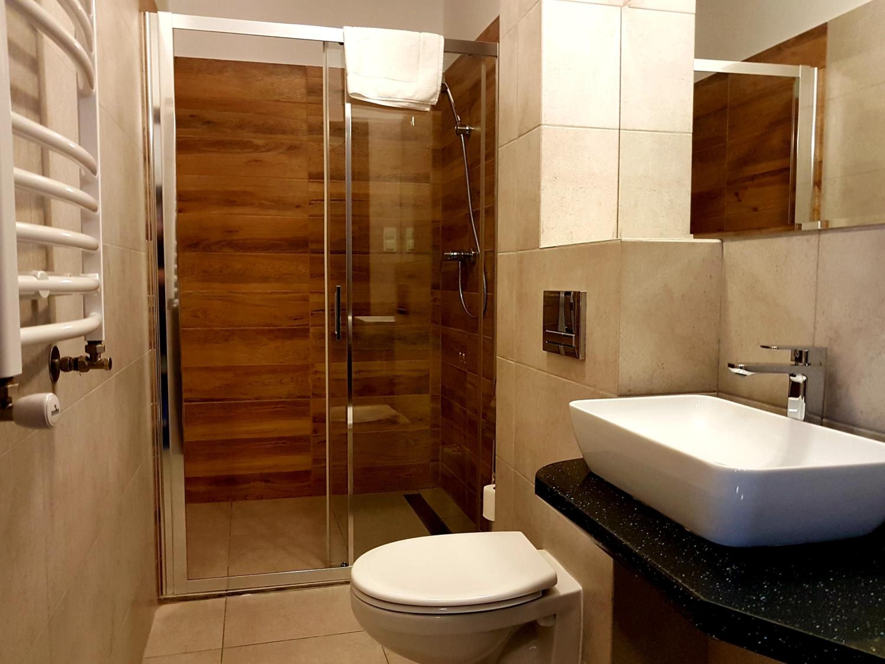 Une salle de bain moderne avec une douche à parois de verre, des toilettes blanches et un lavabo sur un plan de travail noir.