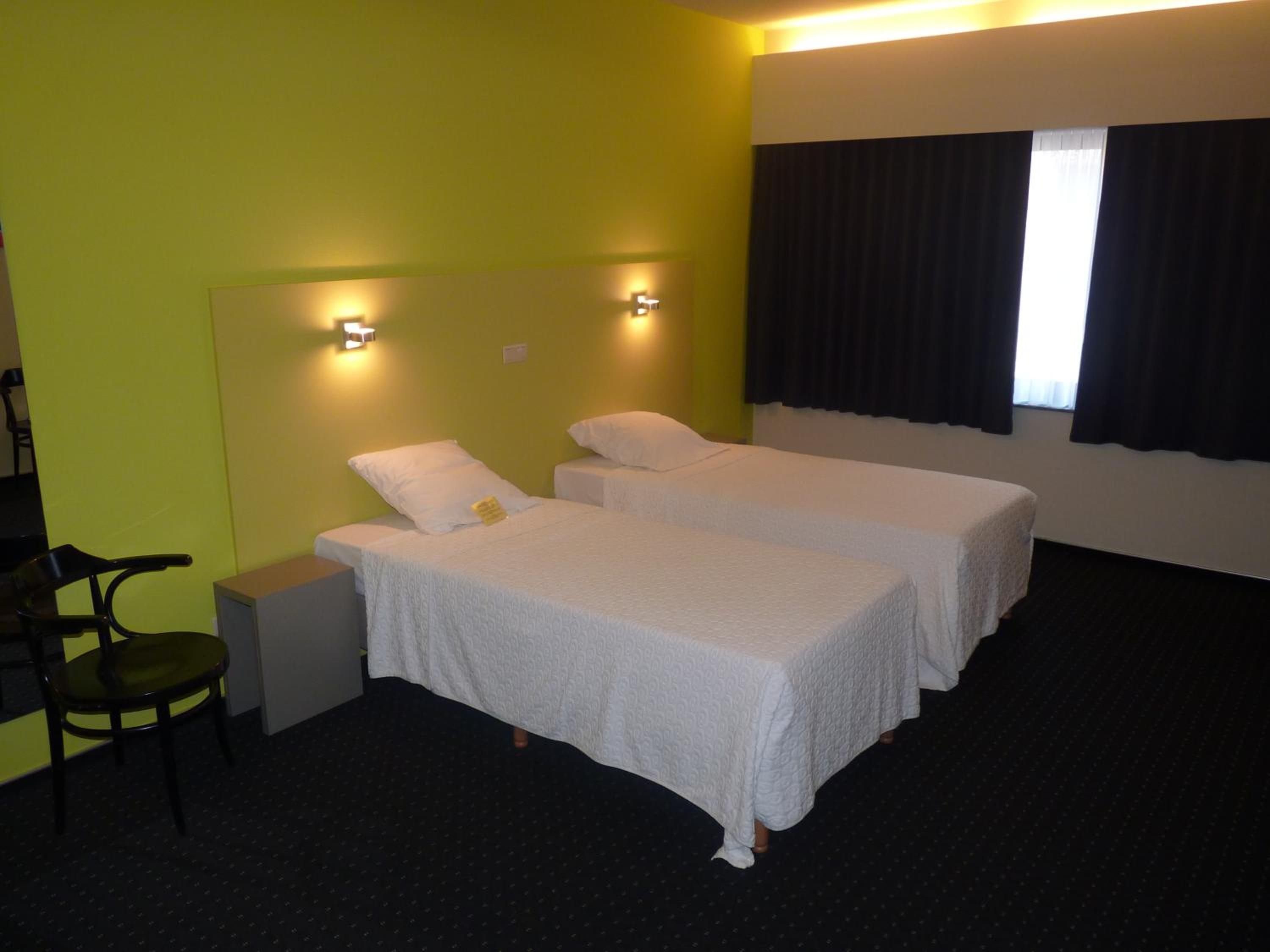 A hotel room with two beds, a desk, and a chair.