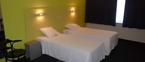 A hotel room with two beds, a desk, and a chair.