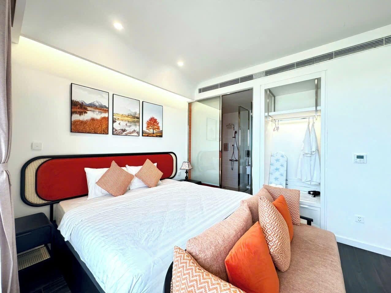 A modern hotel room with a bed, a sofa, a shower area, and a wardrobe.