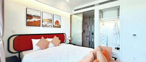 A modern hotel room with a bed, a sofa, a shower area, and a wardrobe.
