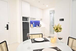 Uma cozinha moderna com armários brancos, uma geladeira preta e um revestimento azul.