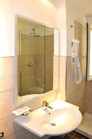 A bathroom with a glass-enclosed shower, a white sink, and a telephone. - Morcavallo Hotel & Wellness (Peschici)