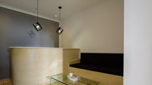 A reception area with a glass coffee table, a counter, and two pendant lights. - Tataki Family Hotel (Santorini)
