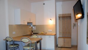A compact kitchen with a dining area, a built-in oven, a sink, and a TV mounted on the wall. - Centrum Konferencyjne Ibib Pan (Warsaw)