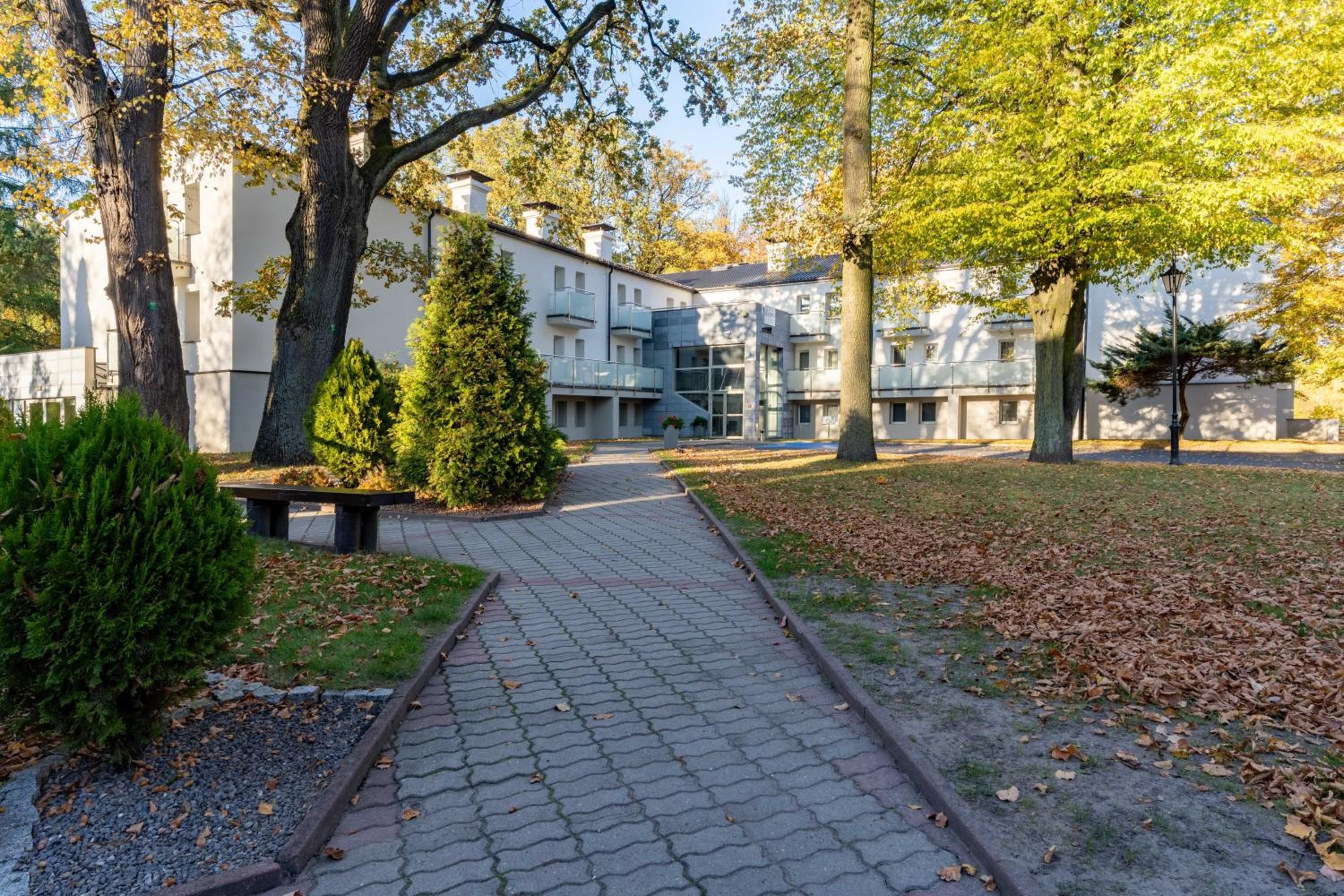 Ein gepflasterter Weg führt zu einem Gebäude mit zahlreichen Fenstern und Balkonen.