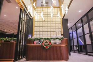 A reception desk with a Christmas wreath, a wooden panel backdrop, and a modern light fixture. - Gaia Hotel Ternate (Ternate)