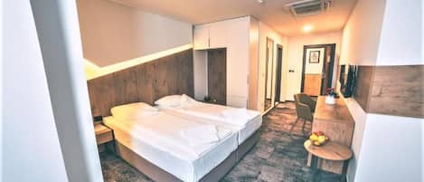 A hotel room with a bed, bedside table, and a small desk with a chair.