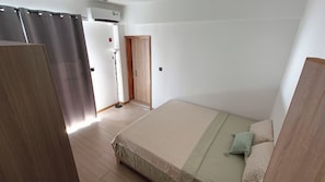 Ein Schlafzimmer mit einem Bett, einem Holzschrank, einer Tür und einer Klimaanlage.