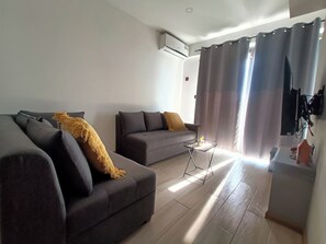 Ein Wohnzimmer mit zwei Sofas, einem kleinen Tisch und einem an der Wand befestigten Fernseher.