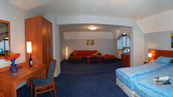 Habitación de hotel con cama, escritorio, silla, sofá y televisor.