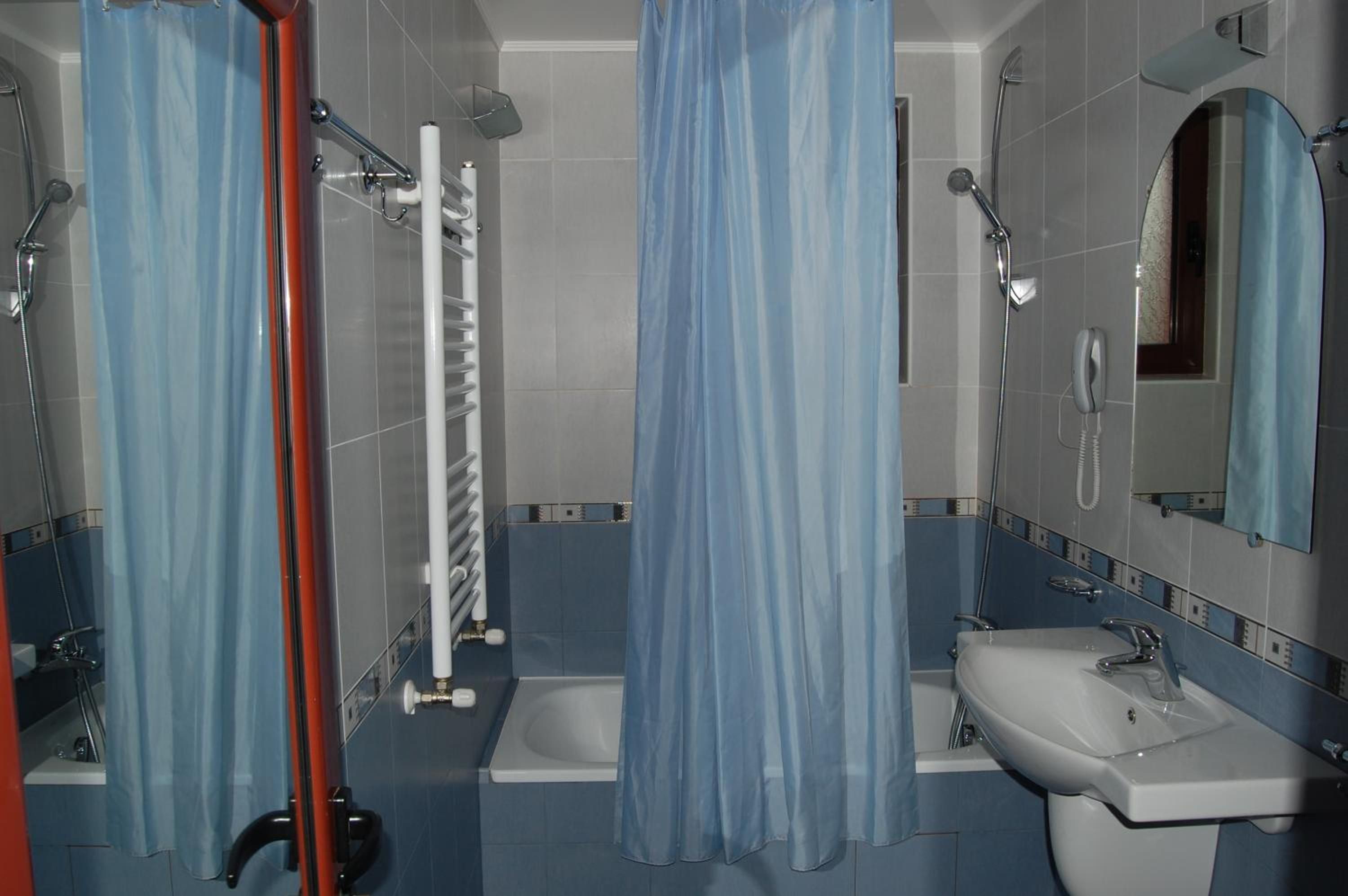 Un baño con ducha, inodoro, lavamanos y espejo.