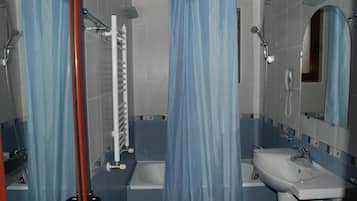 Un baño con ducha, inodoro, lavamanos y espejo.