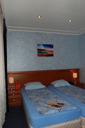 A hotel room with a large bed, two bedside tables, a nightstand, a painting on the wall, and a window with curtains. - Hotel Kibella (Sofia)