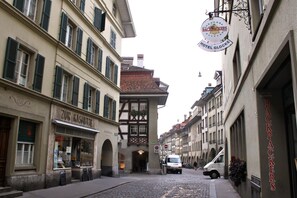A narrow street with buildings on either side, including a hotel named 'Zur Koshutte' and a sign for 'Hotel Glocke'. - Bern Backpackers Hotel Glocke (Bern)
