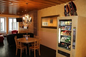 A dining area with a chandelier, a vending machine, and a television on the wall. - Bern Backpackers Hotel Glocke (Bern)