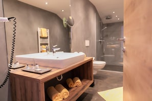 Ein modernes Badezimmer mit einem Doppelwaschbecken, einem Spiegel, einem Handtuchhalter und einer Duschkabine.
