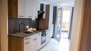 A modern kitchen with a built-in oven, a sink, and a window overlooking a balcony. - Weisses Lamm (Hallstatt)