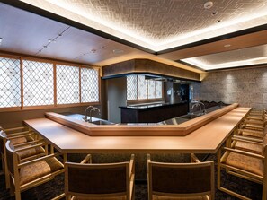 A modern kitchen with a central island, bar seating, and a view through a patterned window. - Shikinoirodori Hatago (Kobe)