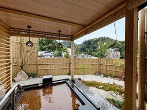 A traditional Japanese onsen with a wooden roof, a stone hot spring, and a bamboo fence. - Shikinoirodori Hatago (Kobe)