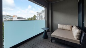 A balcony with a sofa and a small table, a view of buildings, and a clear sky. - Shikinoirodori Hatago (Kobe)
