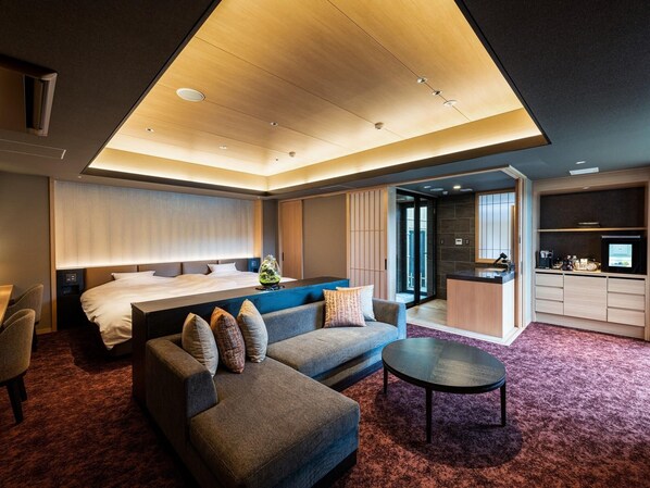 A modern hotel room with a bed, sofa, coffee table, and kitchenette. - Shikinoirodori Hatago (Kobe)