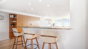 Une cuisine moderne avec des meubles en bois, un plan de travail en marbre et trois tabourets de bar.