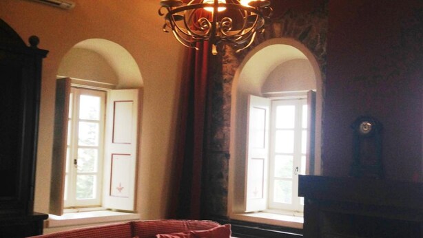 A room with a red sofa, a glass coffee table, a chandelier, and a fireplace. - Pyrgos Of Mystra (Sparta)