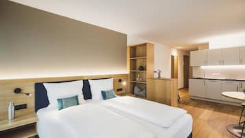 Ein modernes Hotelzimmer mit einem großen Bett, einem Holz-Kopfteil, einem Nachttisch und einer eingebauten Holzablage.