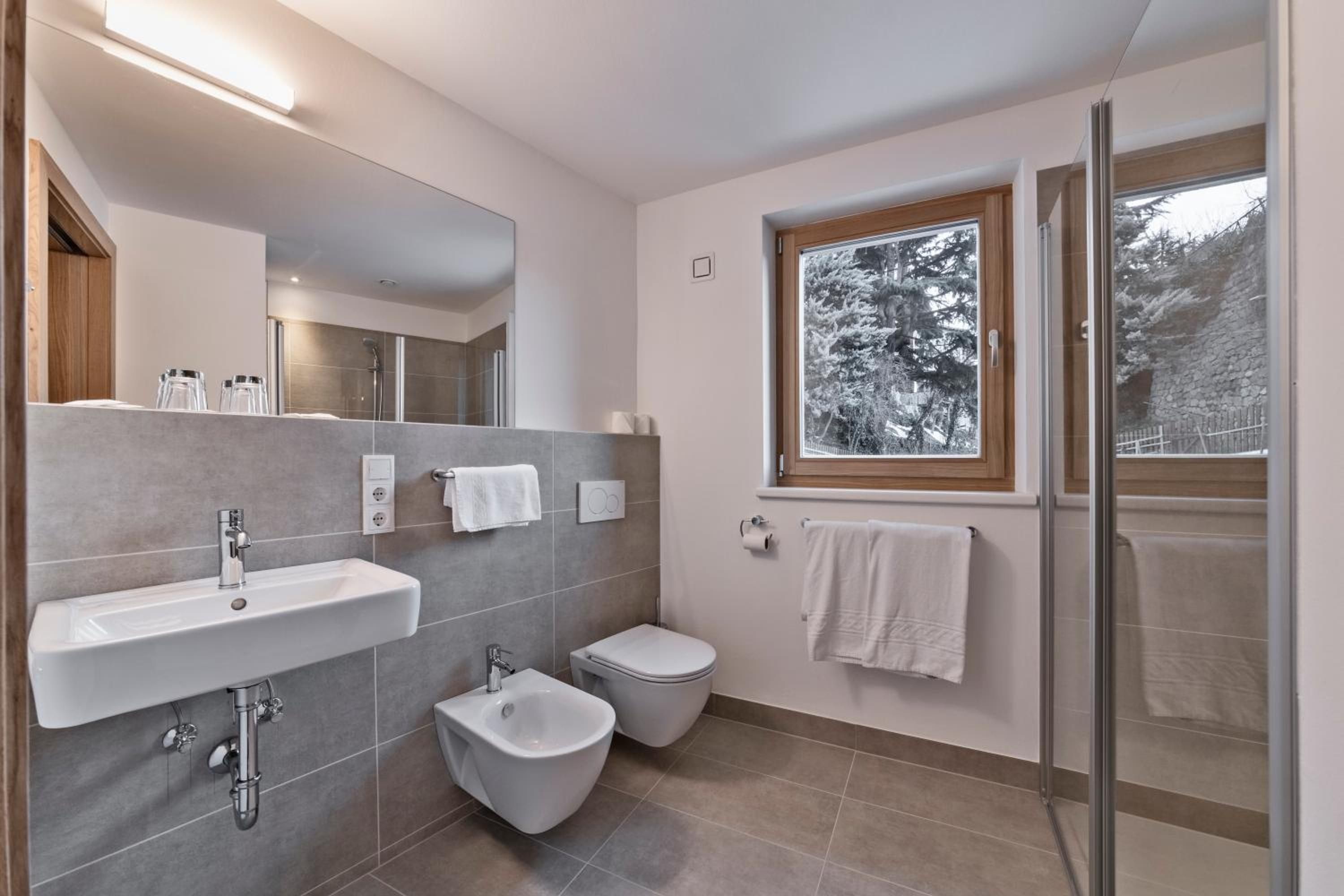 Un bagno moderno con bidet, water e lavandino.