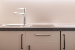 A kitchen with a modern faucet, a flat-screen TV, and minimalist cabinetry. - Residence Nives (Bressanone)