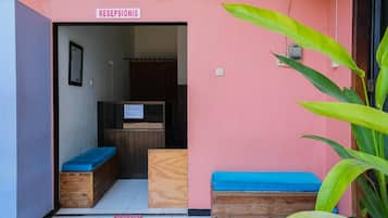 A reception area with a sign, wooden benches, and a plant.