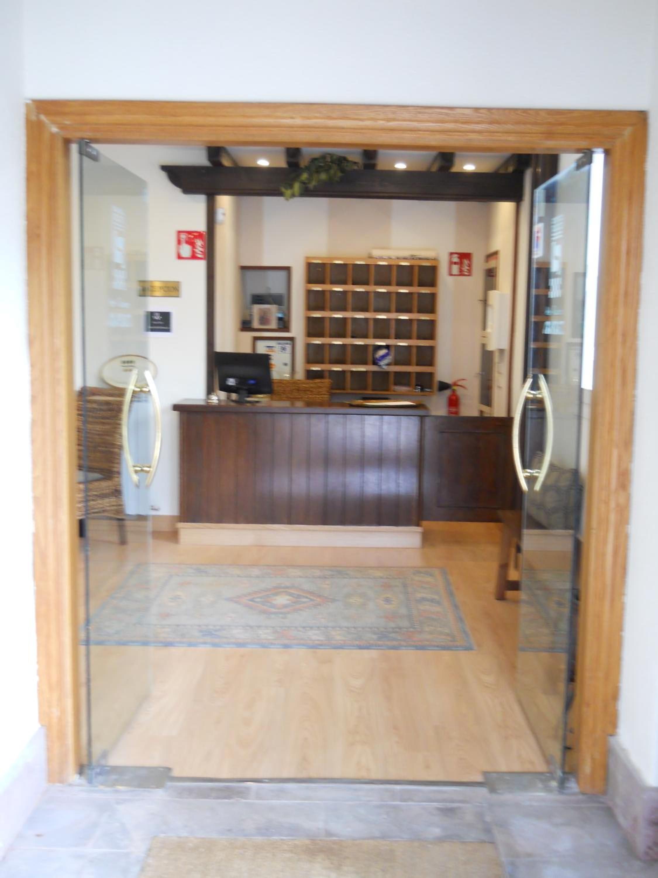 Una zona de recepción con un mostrador de madera, un monitor de computadora y una alfombra estampada.