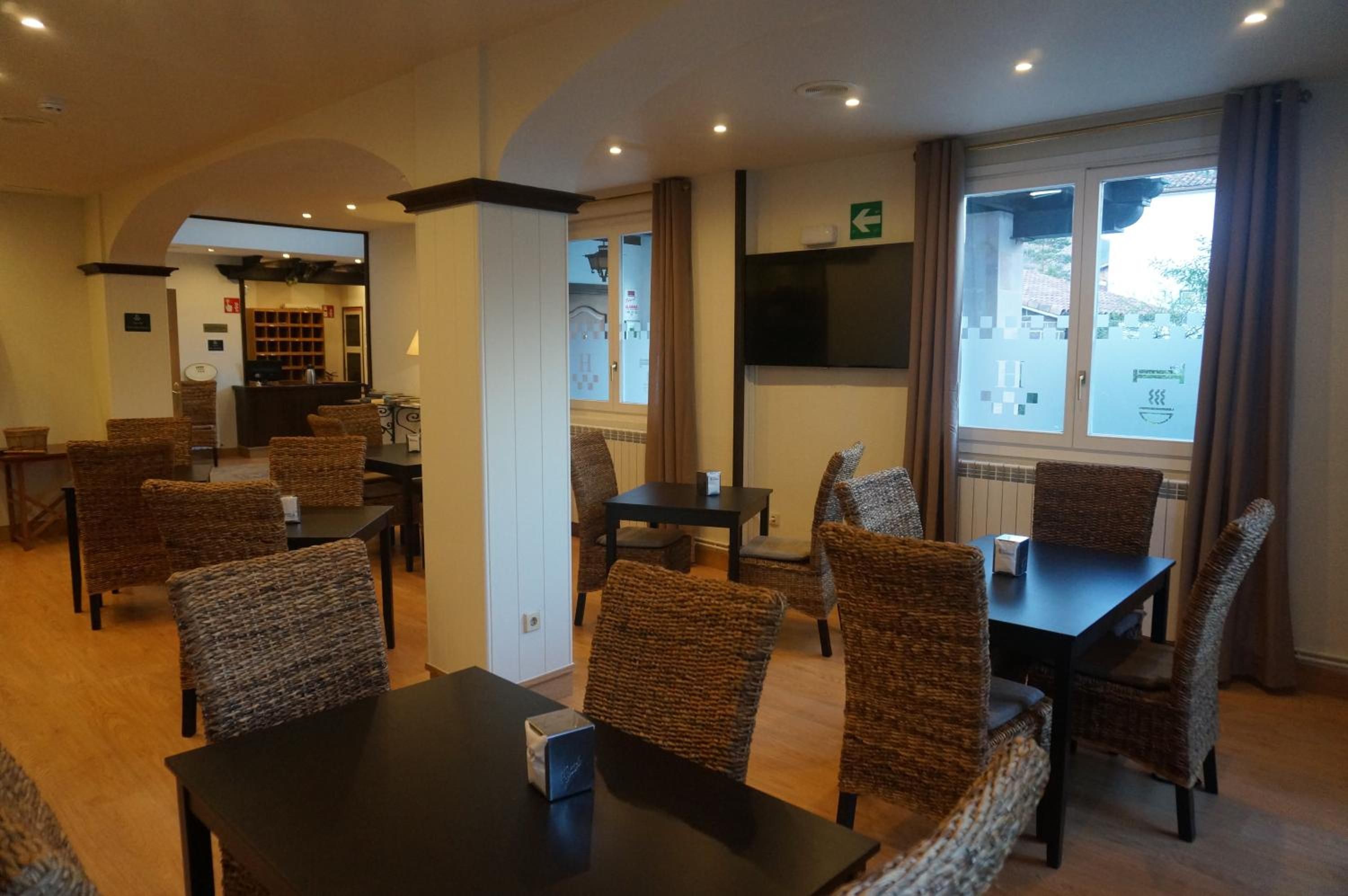 Una habitación de hotel con comedor, mostrador de recepción y televisión.