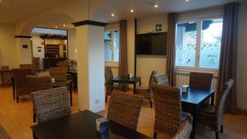 Una habitación de hotel con comedor, mostrador de recepción y televisión.