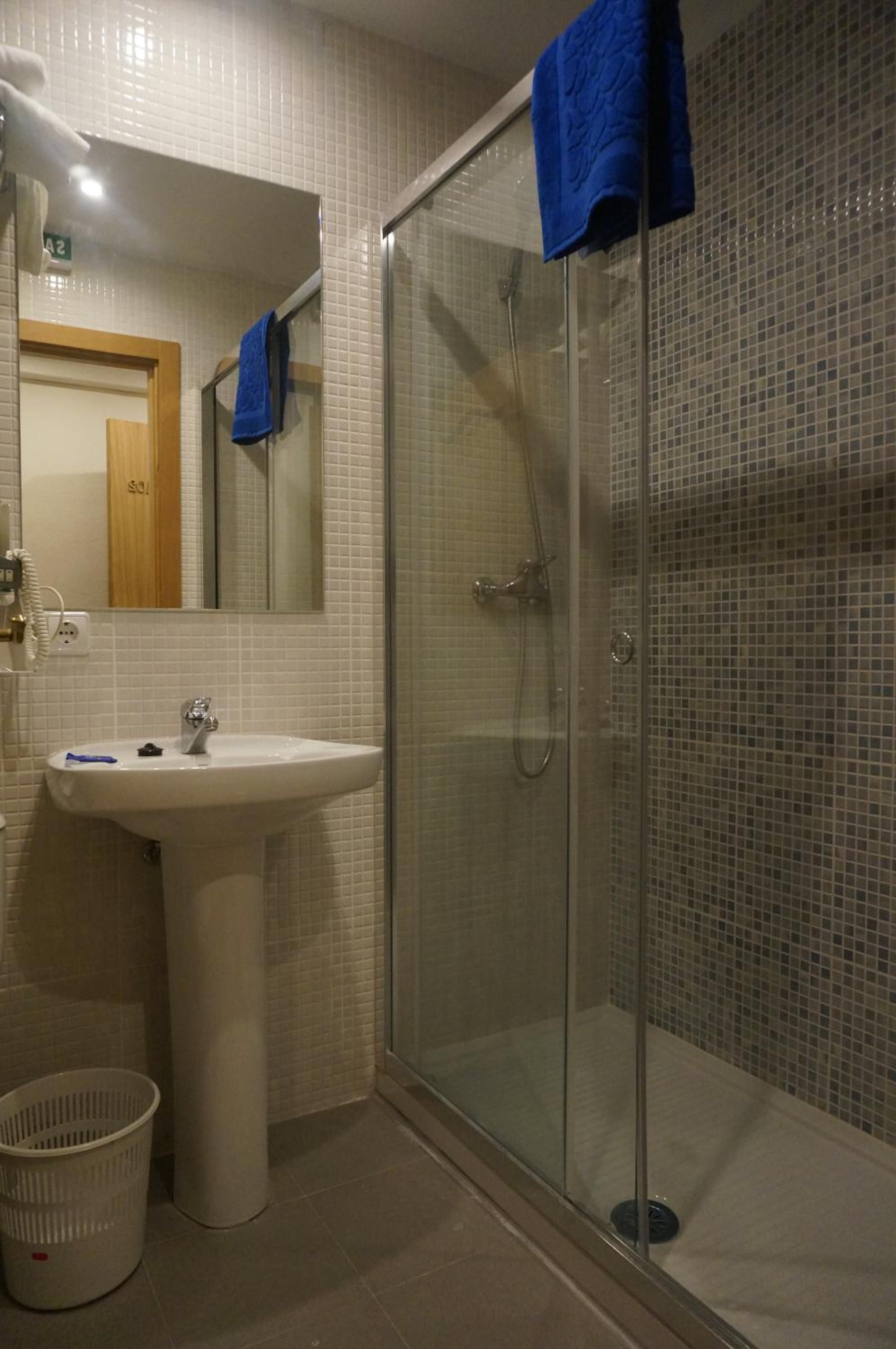 Un baño con cabina de ducha de vidrio, un lavamanos y un espejo.