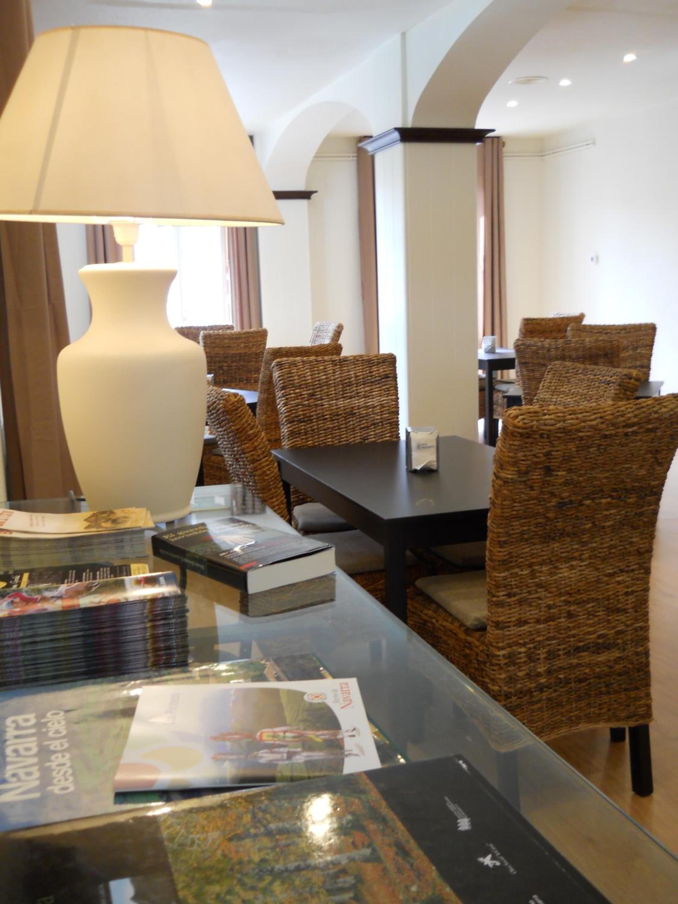 Un comedor de hotel con sillas de mimbre, una mesa de vidrio y una lámpara grande.