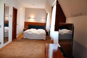 A hotel room with a large bed, a wooden headboard, a mirror, and a wall-mounted light fixture. - Hotel Park Central (Sliven)