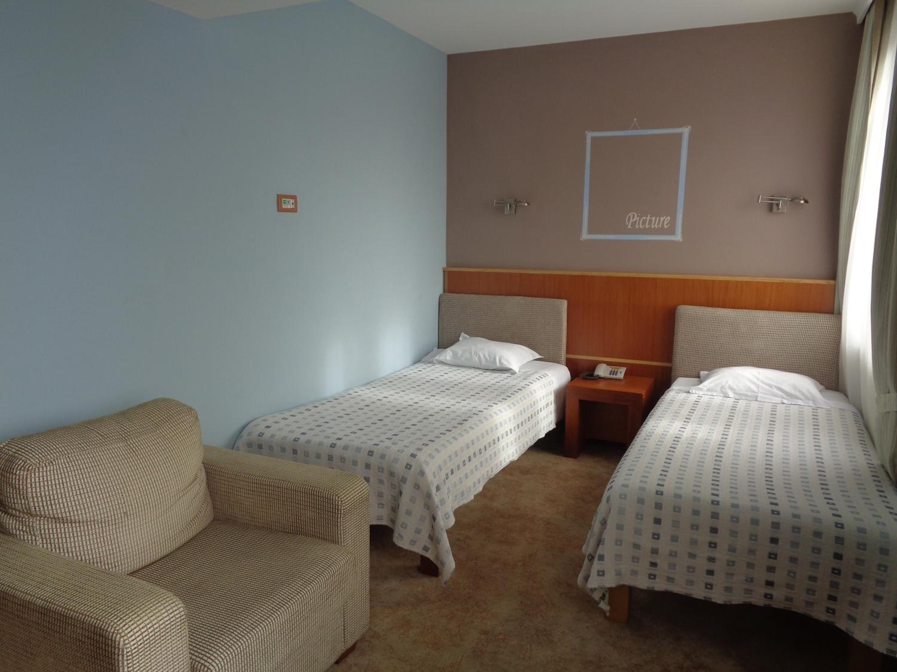 Ett hotellrum med två sängar, en soffa och ett litet sidobord med en telefon.